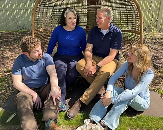 Deirdre and Russ Todd with their two children outdoors on a wicker garden bench