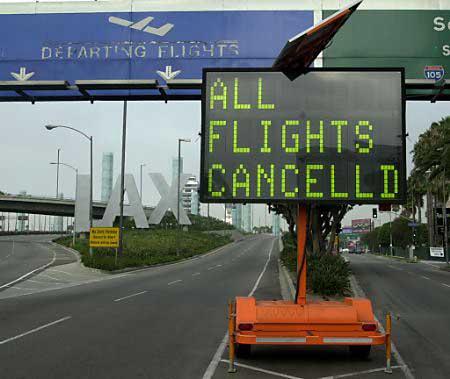 Electronic roadside sign reading All Flights Cancelled at an empty airport entrance