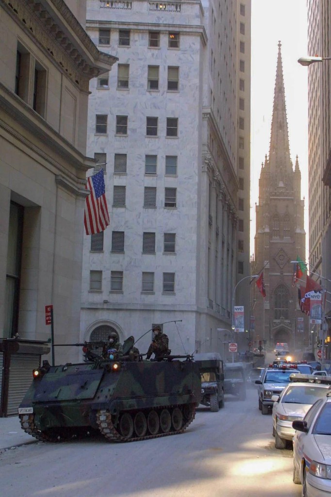 Military armored vehicle and police convoy on a dust-covered street in Lower Manhattan after September 11