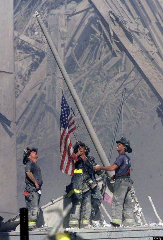 Three firefighters raising the American flag amid the ruins at Ground Zero